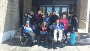 Image of eight people outside  - five standing and three in wheelchairs