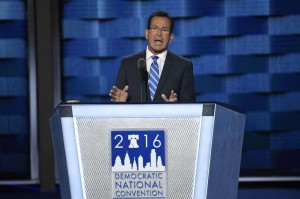 Gov. Malloy speaking at DNC, standing behind podium, wearing black suit, white shirt and blue tie