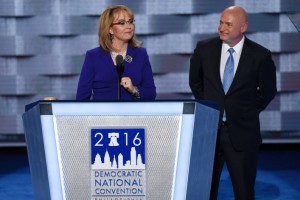 Image of Gabby Giffords speaking behind podium with husband Mark  Kelly standing next to her