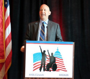 Gov. Jack Markell wearing a gray suit talking behind a podium with the text: #ABLE2WORK #ADA26