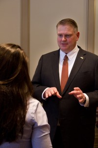 State Sen. Colin Bonini standing, wearing a suit with a red tie, talking to a constituent