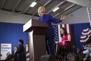 Hillary Clinton speaking in Orlando behind a pocium with Anastasia Somoza seated in a power wheelchair next to her