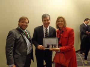 Governor Roy Cooper, Jennifer Mizrahi, and Phillip Pauli smiling, as Gov. Cooper and Jennifer Mizrahi hold an award from RespectAbility