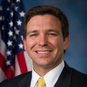 Ron Desantis smiles in front of an American flag