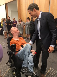 Beto O'Rourke speaks to a caucasian man in a power wheelchair