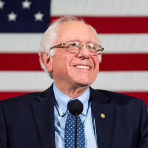Bernie Sanders smiling in front of an American flag