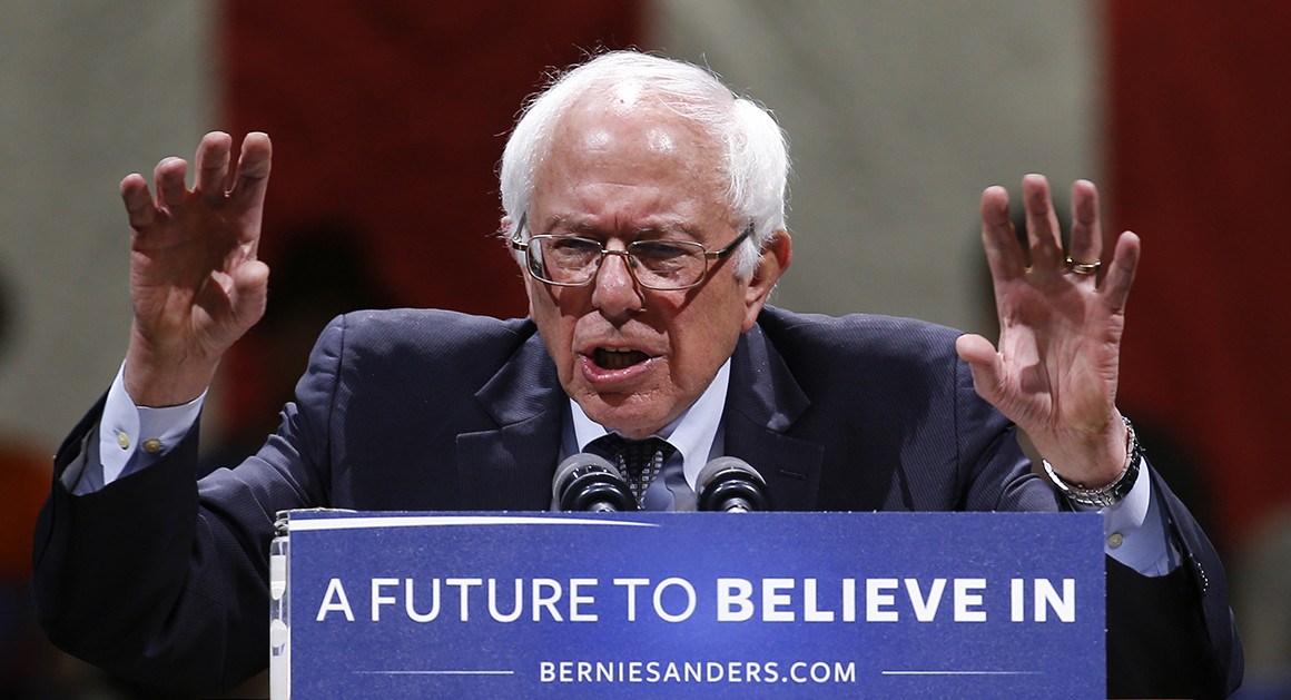 Image of Bernie Sanders standing behind podium with sign saying A Future to Believe