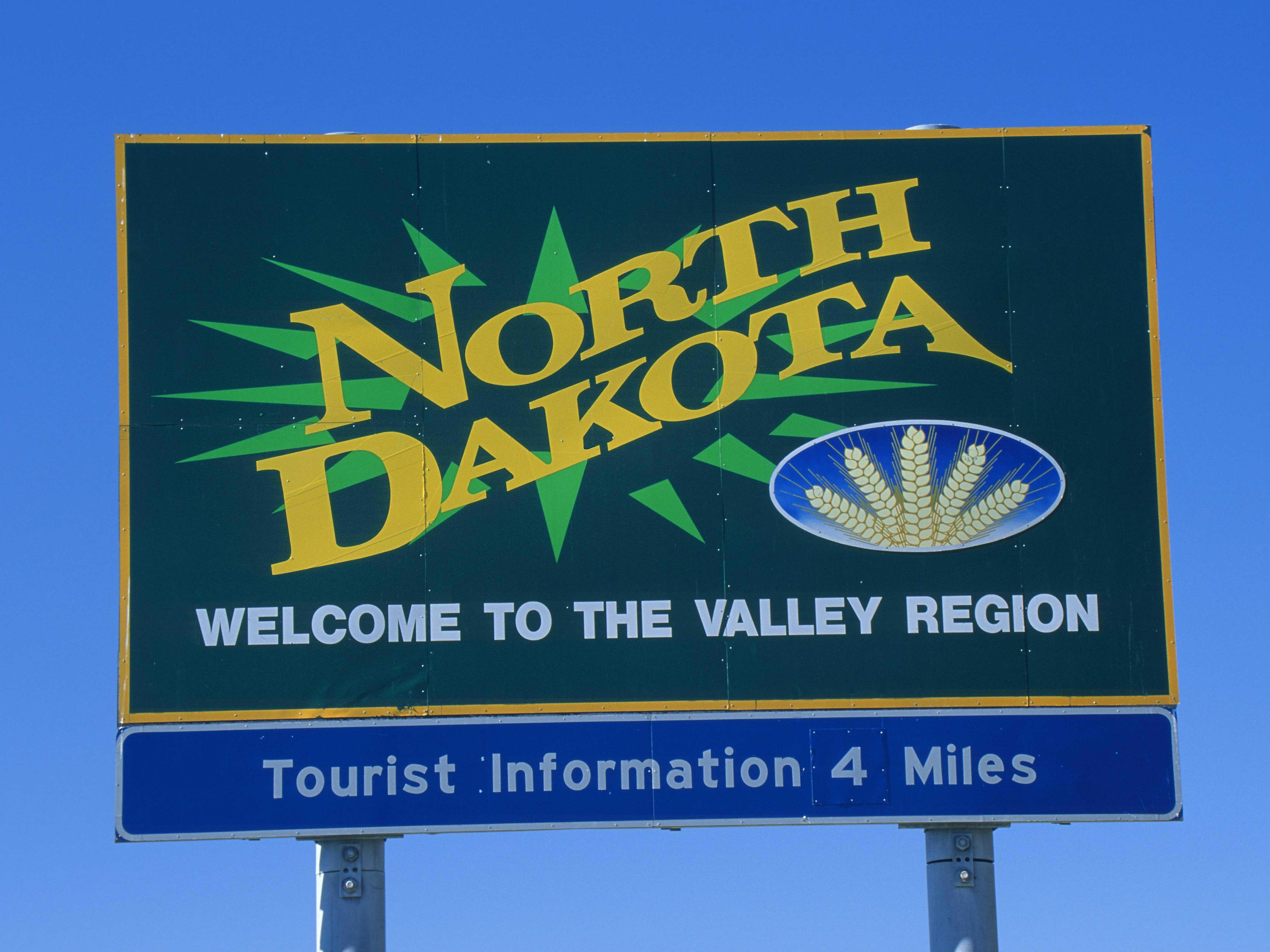 Green sign with text: North Dakota: Welcome to the Valley Region / Tourist Information: 4 Miles
