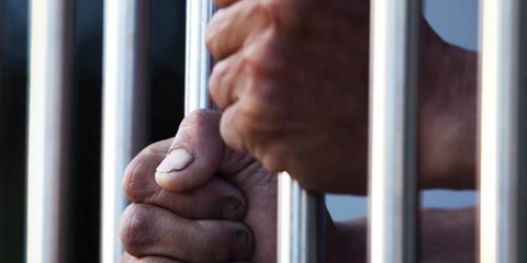 Hands behind prison bars