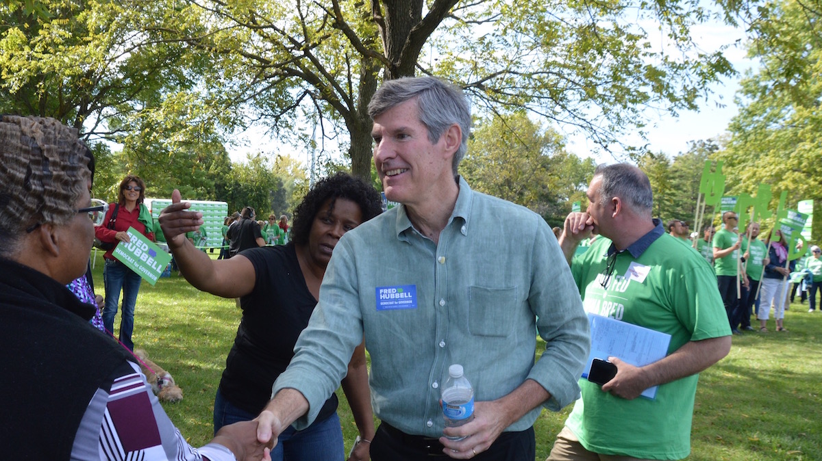 Fred Hubbell shakes hands with supporters in a park