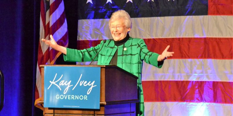 Kay Ivey speaks in front of an American Flag at her election night victory party