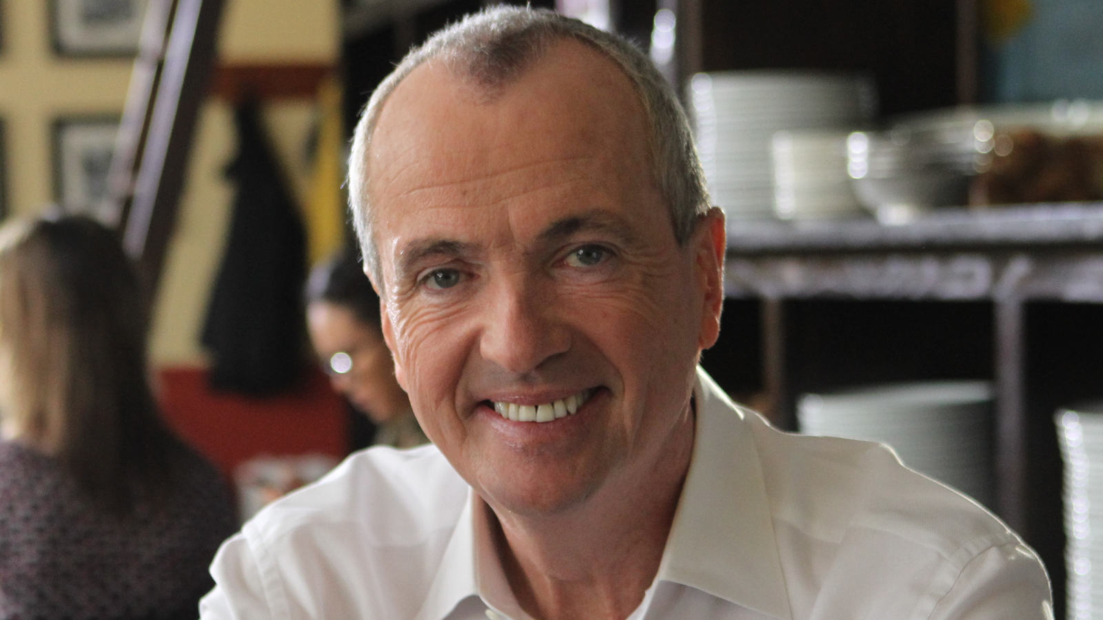 Gov. Phil Murphy smiling wearing a white collared shirt