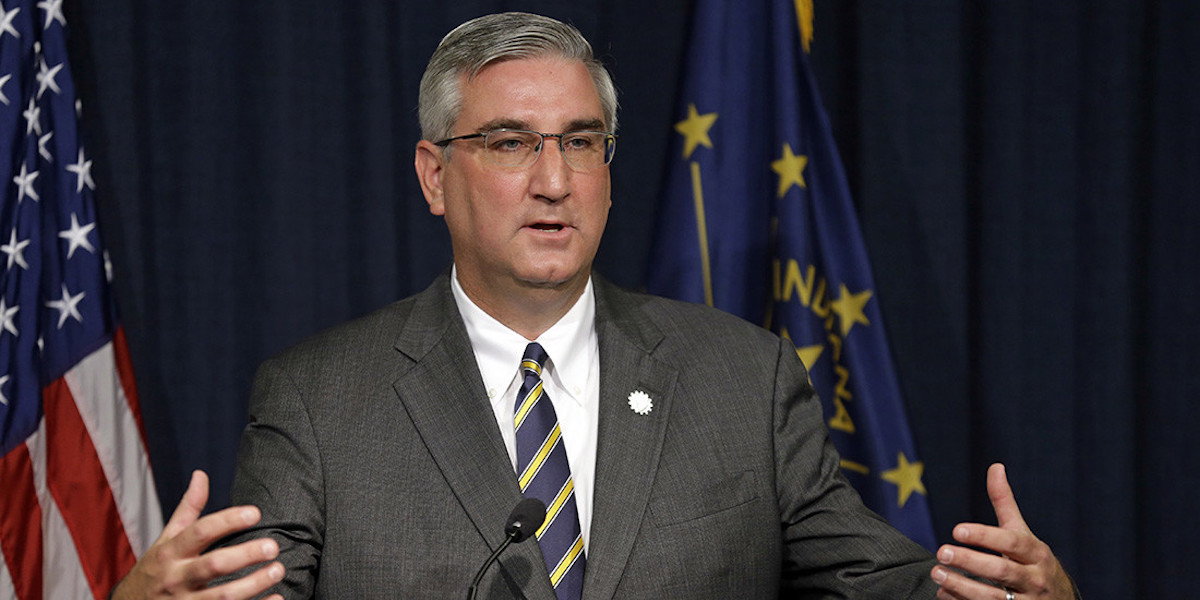 Governor Eric Holcomb gives a speech in front of flags for America and the state of Georgia