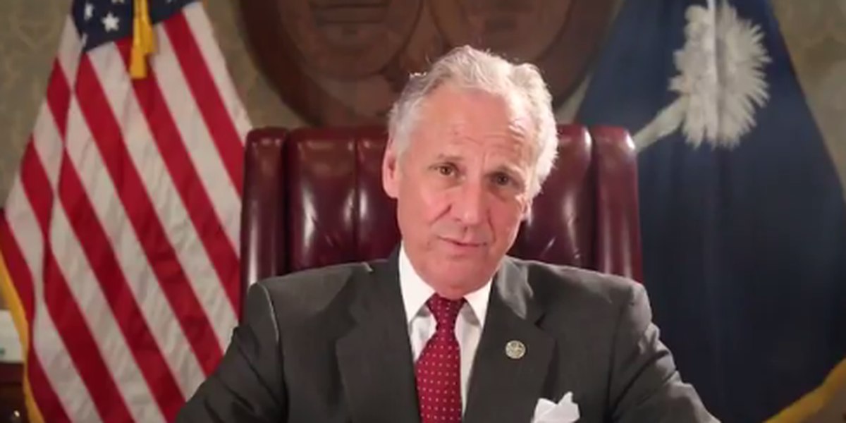 Governor Henry McMaster sitting at his desk in front of an American Flag and a South Carolina state flag giving a speech