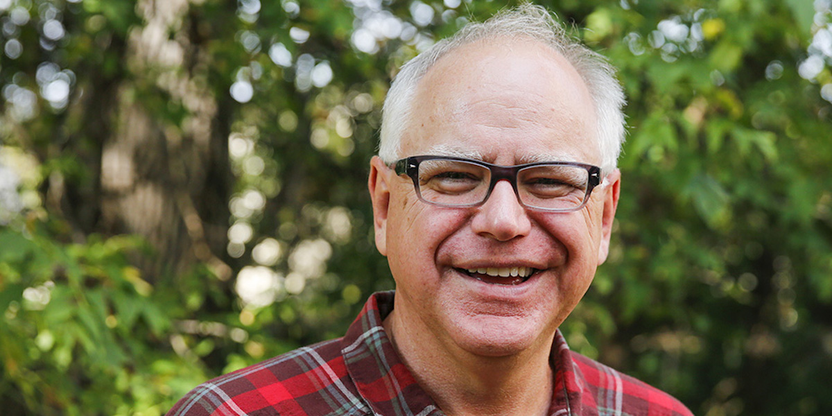 Governor Tim Walz smiles in front of trees
