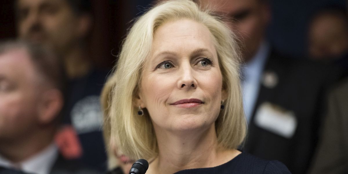 Kirsten Gillibrand smiling in front of a blurred crowd background