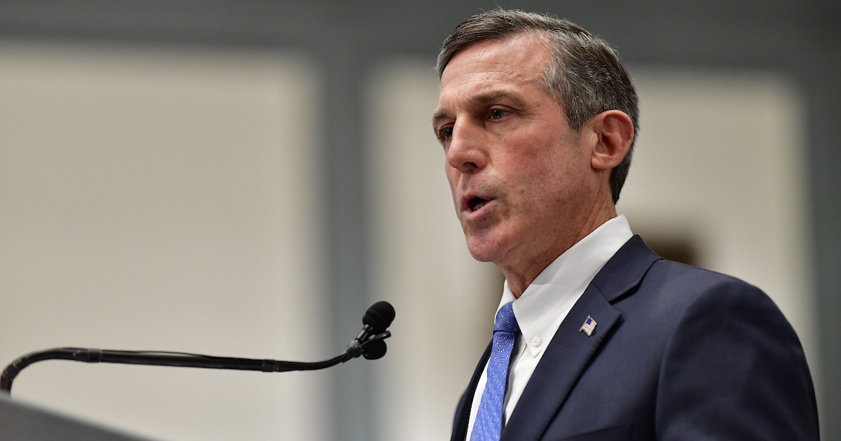 Governor John Carney speaking into a microphone wearing a suit and tie